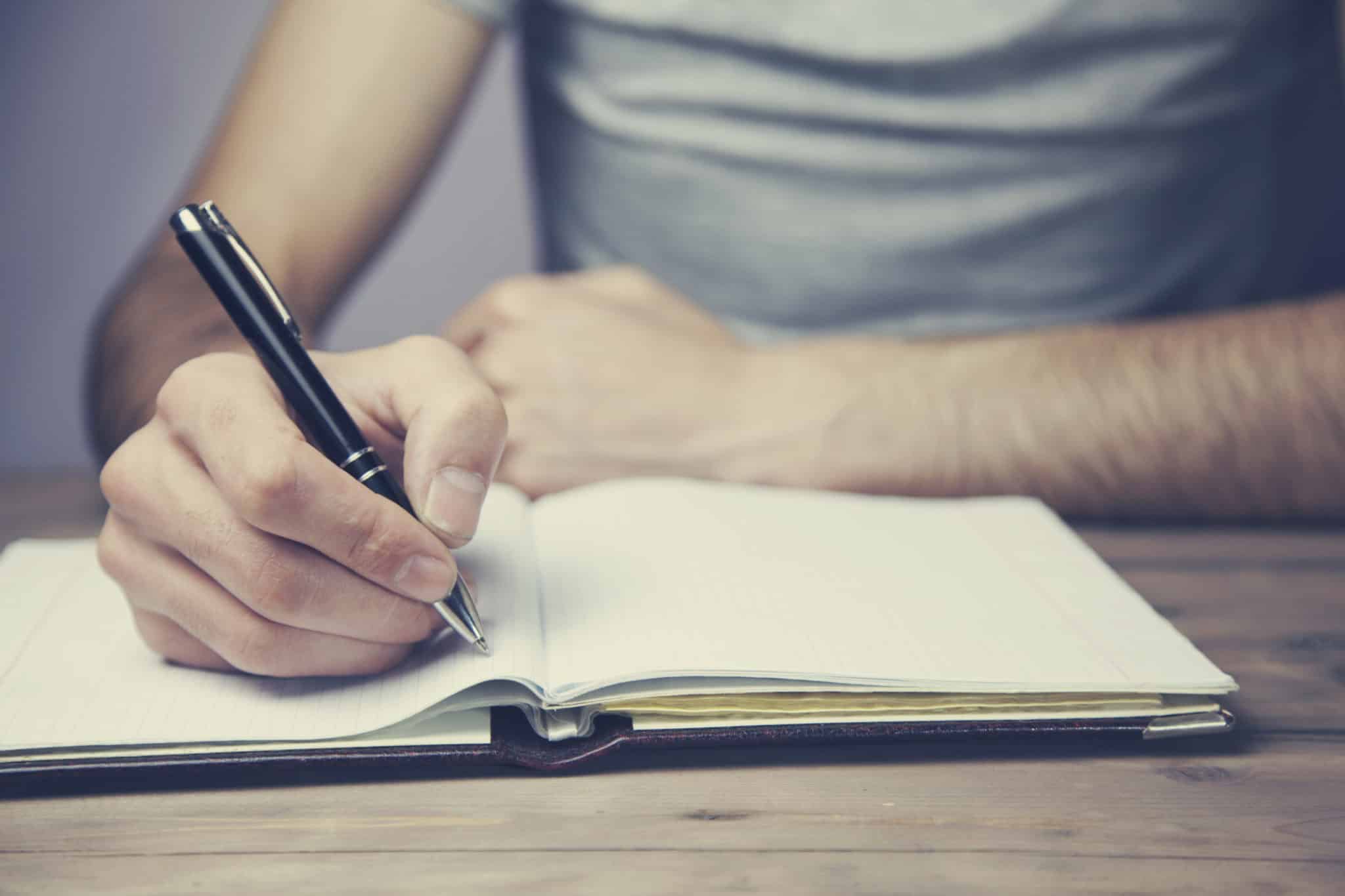 man hand pen and notebook on wooden table