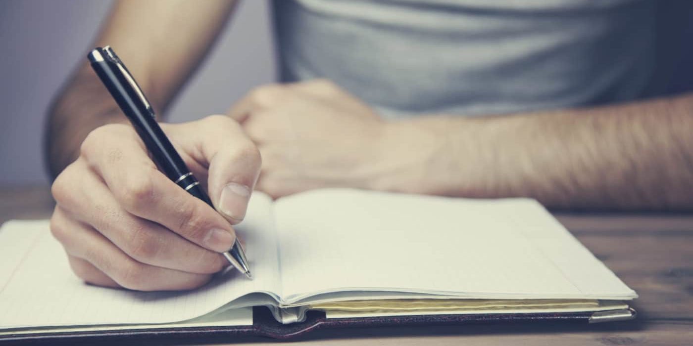 man hand pen and notebook on wooden table