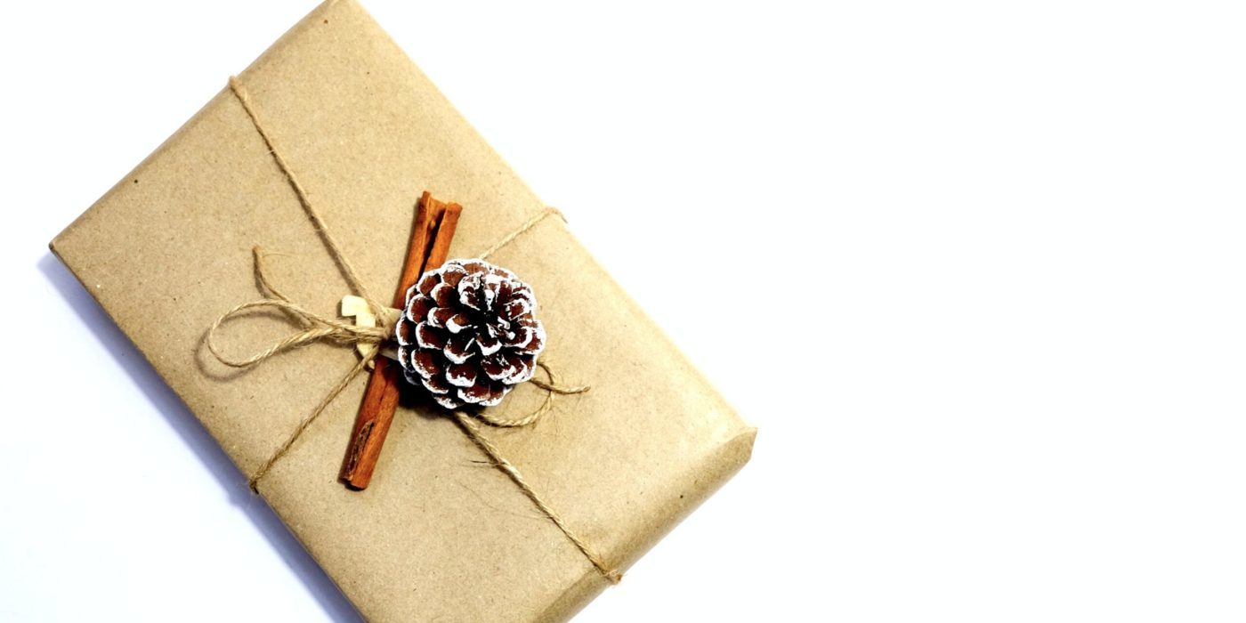 present wrapped in brown paper with a pinecone on a white background