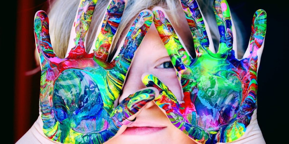 Child holding up hands with swirled paint very colorful